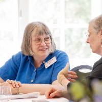 Dianna Johnson sitting at table talking with another woman at event